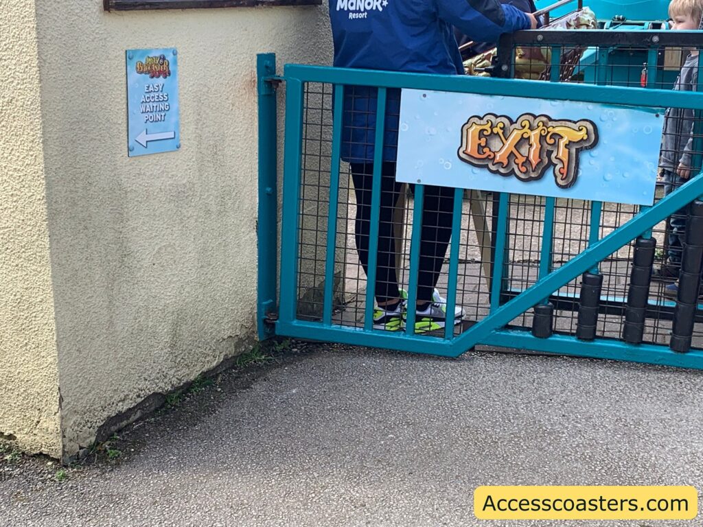 in the image you can see a blue gate with a large saying exit. to the side their is a sign saying easy access wait here