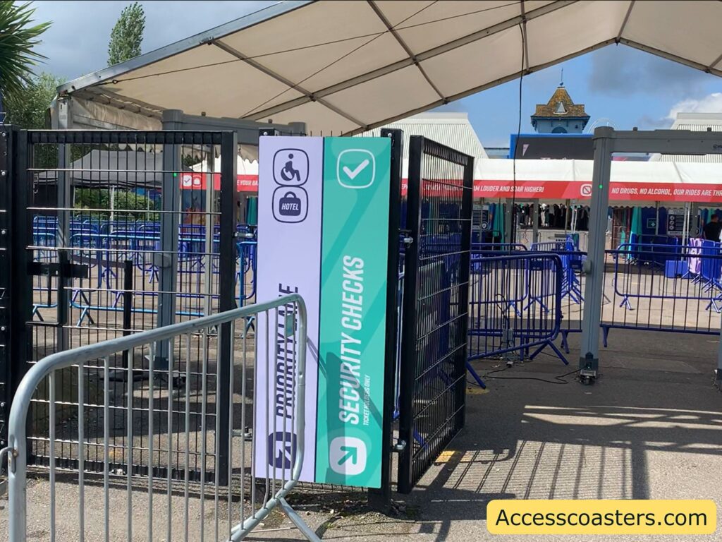 Priority security lane entrance at Thorpe Park, showing an accessible gate with a sign for disabled visitors and security checks under a canopy, with metal barriers guiding the queue.