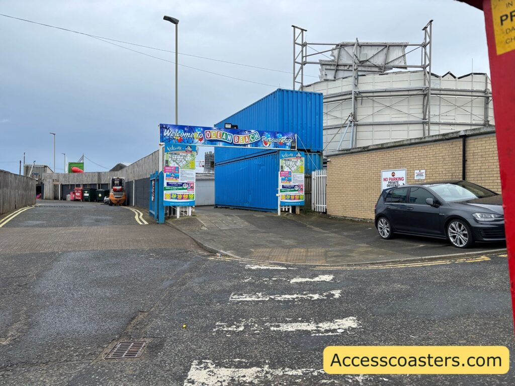 image of ocean beach entrance taken from across the road. There is an ocean beach entrance arch with branded signage, prices and information.