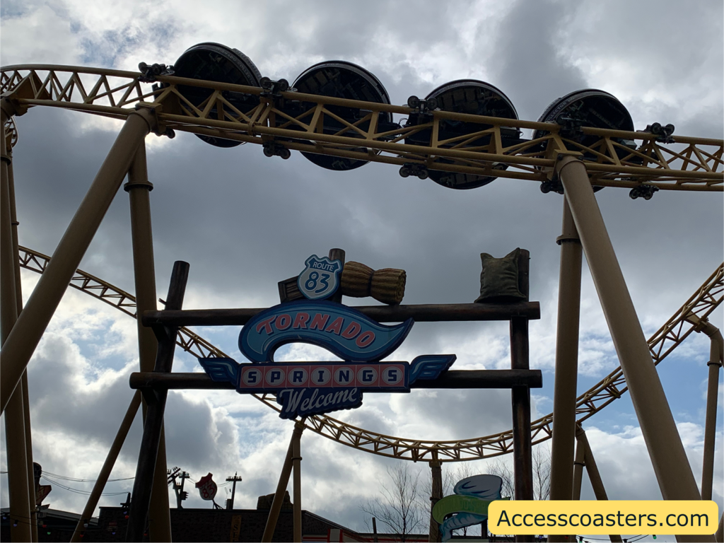 Image shows Tornado Springs area entrance sign. You can also see Storm Chaser going around above the sign.