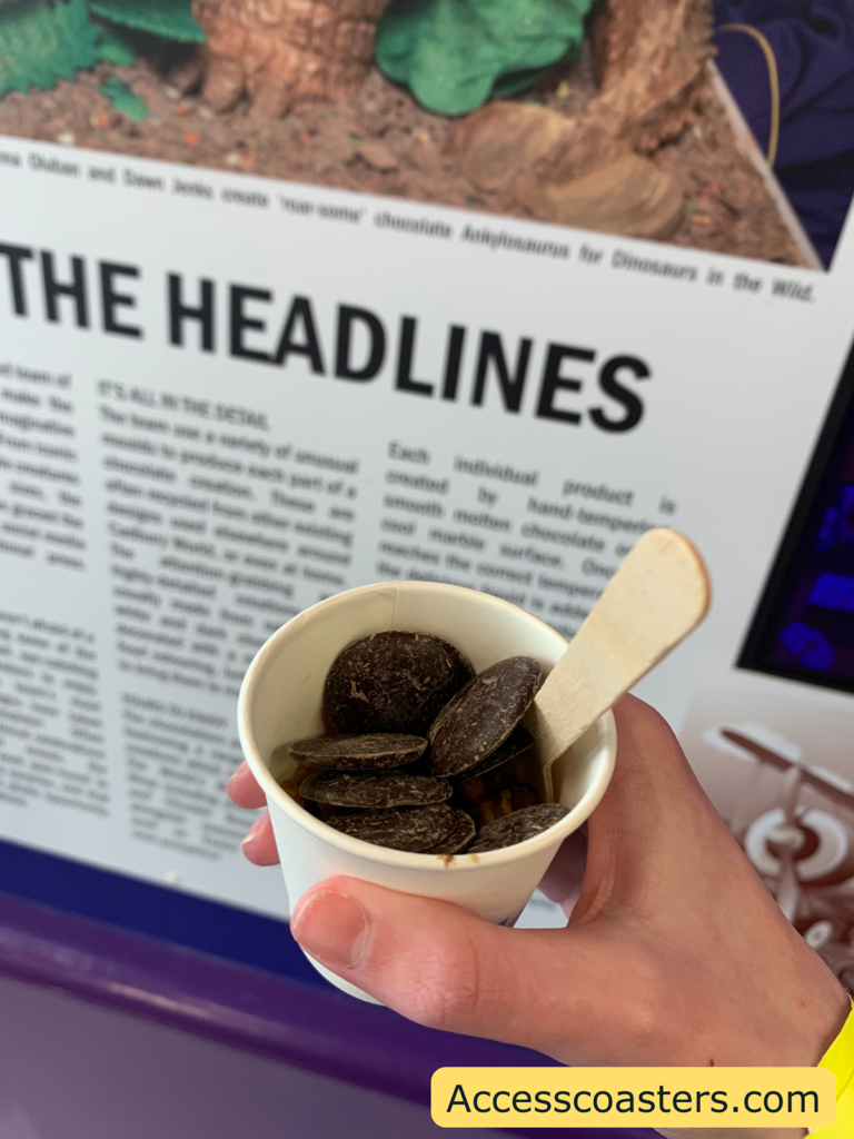 Image of melted chocolate pot. You can see chocolate buttons in a white cup with a paper spoon.
