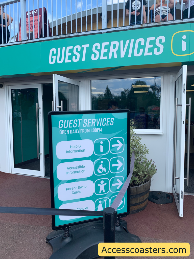 In the image you can see entrance to guest services with a sign outside saying help and information, accessibility information, parent swap cards and hight check. 