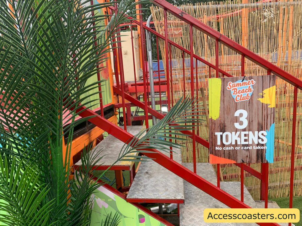 in the image you can see stairs leading up to the caterpiller coaster entrance with a sign saying 3 tokens 