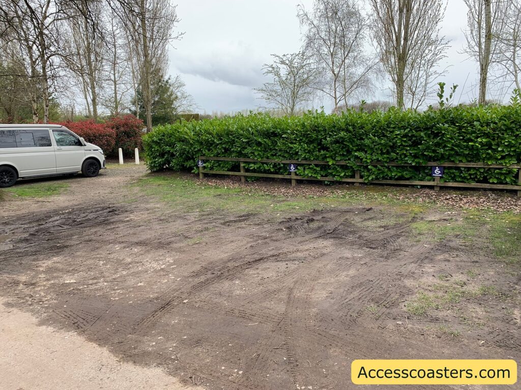 Image shows a muddy car park with blue badge parking signs