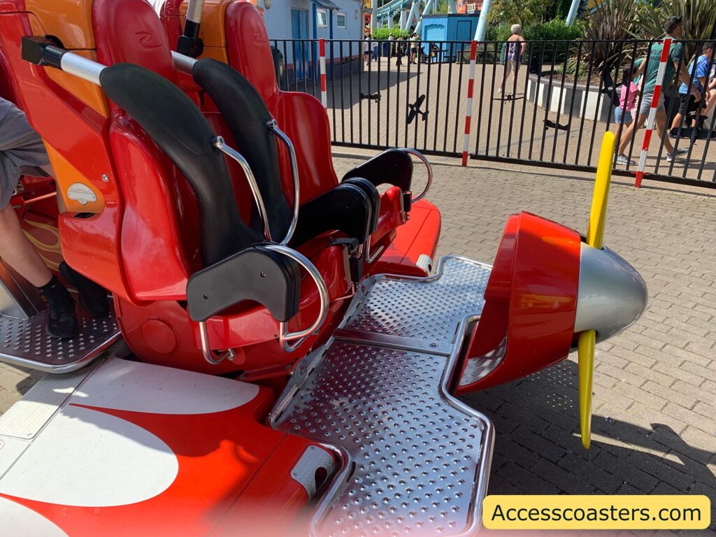 in the image you can see the from row of an air racer ride vehicle it is red and made to look like an airplane. the seats have over the shoulder restraints.  