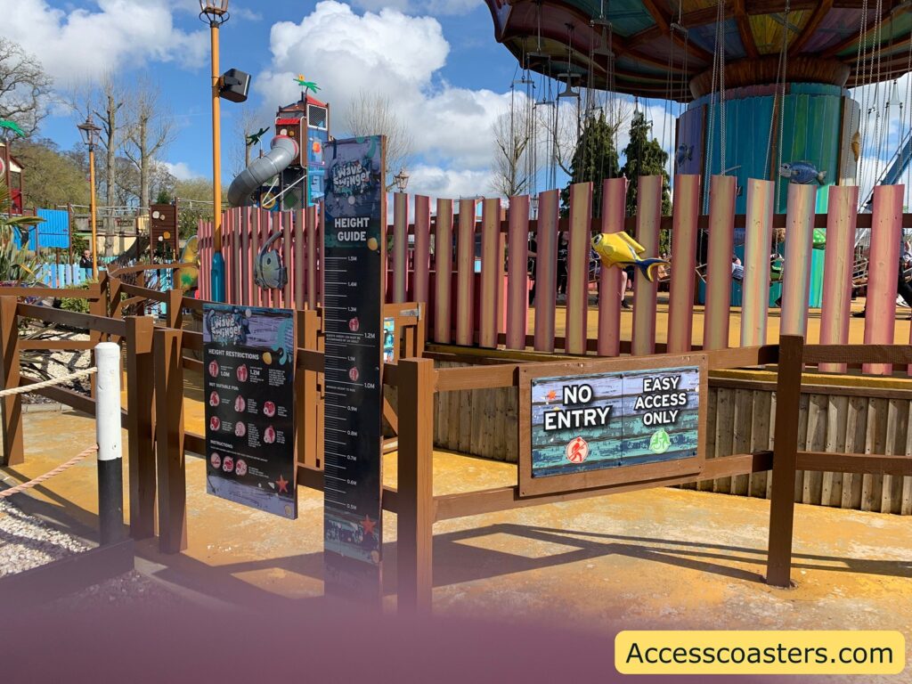 image shows ride restrictions board,  and easy access entrance for wave swinger. there is a sign that reads exit easy access only