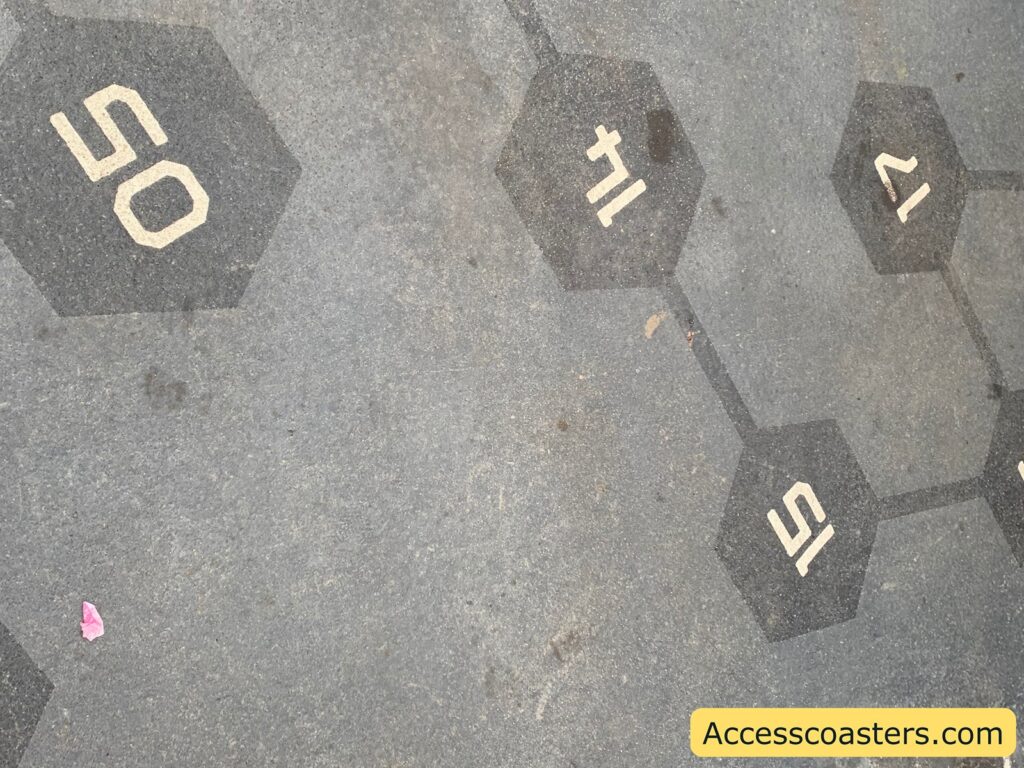 Hexagonal shapes on a surface, each containing a number or symbol. The visible numbers and symbols are "50", "11", "15", and "12". The hexagons are connected by lines, resembling a molecular structure. In the bottom right corner, there is a yellow rectangle with the text "Accesscoasters.com". A small pink object is on the surface near the hexagon with "50".