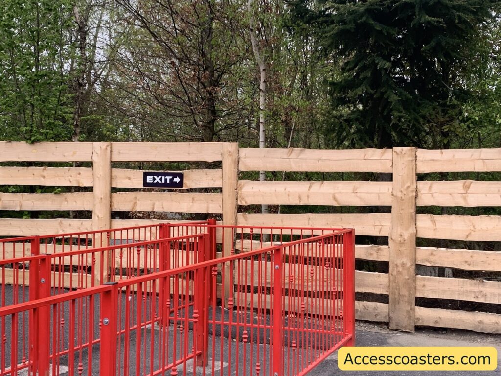 Image shows red railings formed to make a queue line and a sign next to the railing tha reads exit