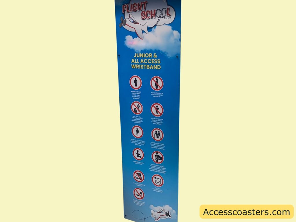 all blue sign with white clouds, displaying rules and restrictions for a ride called "Flight School." At the top, there is an illustration of a small airplane and the words "Flight School." Below, it says "JUNIOR & ALL ACCESS WRISTBAND" Minimum three years old. There is a figure of a person.
2. Not suitable for pregnant riders. Icon shows a pregnant woman.
3. Not suitable for guests with broken limbs or plaster casts. Icon shows a person with a cast.
4. Not suitable for guests with heart, neck, or back problems. Icon shows a person holding their back.
5. Wheelchair users must be able to walk unaided to the ride platform. Icon shows two people, one in a wheelchair.
6. Unaccompanied height must exceed a certain line (not fully visible in the image). Icon shows a person standing next to a height marker.
7. Loose articles are not permitted. Icon shows a bag with a line through it.
8. Cameras and photography are not permitted. Icon shows a camera with a line through it.