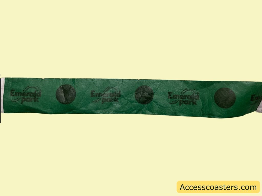 Green paper wristband with the words "Emerald park" repeatedly printed in black, along with black circles between the text. 