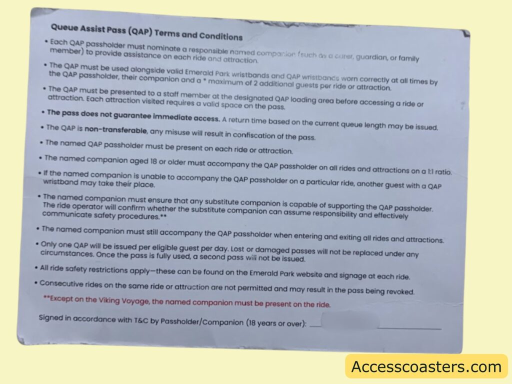  printed card with the title "Queue Assist Pass (QAP) Terms and Conditions." The card lists rules and instructions for using a Queue Assist Pass at Emerald Park. Here is the text transcribed verbatim:

Queue Assist Pass (QAP) Terms and Conditions

• Each QAP passholder must nominate a responsible named companion (such as a carer, guardian, or family member) to provide assistance on each ride and attraction.
• The QAP must be used alongside valid Emerald Park wristbands and QAP wristbands worn correctly at all times by the QAP passholder, their companion and a *maximum of 2 additional guests per ride or attraction.
• The QAP must be presented to a staff member at the designated QAP loading area before accessing a ride or attraction. Each attraction visited requires a valid space on the pass.
• The pass does not guarantee immediate access. A return time based on the current queue length may be issued.
• The QAP is non-transferable, any misuse will result in confiscation of the pass.
• The named QAP passholder must be present on each ride or attraction.
• The named companion aged 18 or older must accompany the QAP passholder on all rides and attractions on a 1:1 ratio.
• If the named companion is unable to accompany the QAP passholder on a particular ride, another guest with a QAP wristband may take their place.
• The named companion must ensure that any substitute companion is capable of supporting the QAP passholder. The ride operator will confirm whether the substitute companion can assume responsibility and effectively communicate safety procedures.**
• The named companion must still accompany the QAP passholder when entering and exiting all rides and attractions.
• Only one QAP will be issued per eligible guest per day. Lost or damaged passes will not be replaced under any circumstances. Once the pass is fully used, a second pass will not be issued.
• All ride safety restrictions apply—these can be found on the Emerald Park website and signage at each ride.
• Consecutive rides on the same ride or attraction are not permitted and may result in the pass being revoked.

**Except on the Viking Voyage, the named companion must be present on the ride.

Signed in accordance with T&C by Passholder/Companion (18 years or over): ___________