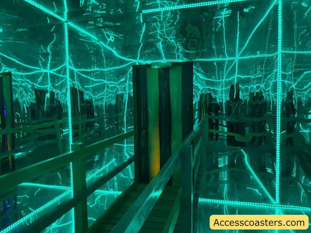 Mirror maze with teal LED lighting. The image shows a walkway with railings leading into a room where the walls, floor, and ceiling are covered in mirrors, creating infinite reflections and a disorienting effect. Bright teal LED strips outline the edges, adding to the surreal atmosphere. 