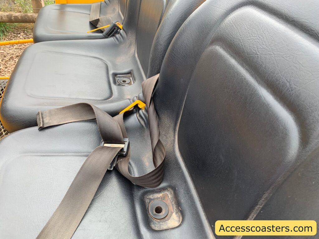 Close-up view of plastic molded seat for the ground shuttle There are individual seats with seat belts fastened across them, featuring yellow clasps.