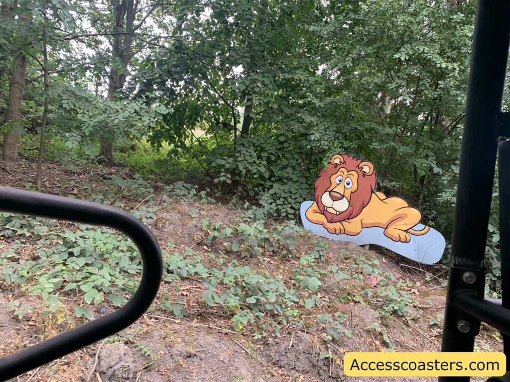 Cartoon lion cutout in a forested area.