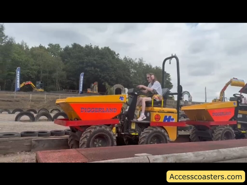 Iona driving a small four-wheeled yellow and red vehicle labeled "DIGGERLAND." Another identical vehicle is visible right behind. The vehicles are on a dirt track bordered with tires and wooden beams.