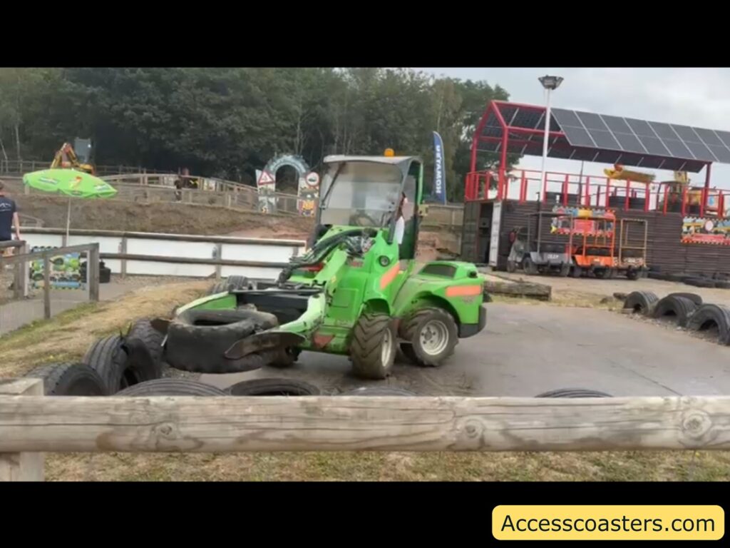 image if iona on a green digger picking up a tire with the digger and puttting it on a pile in the corner of a few other tires