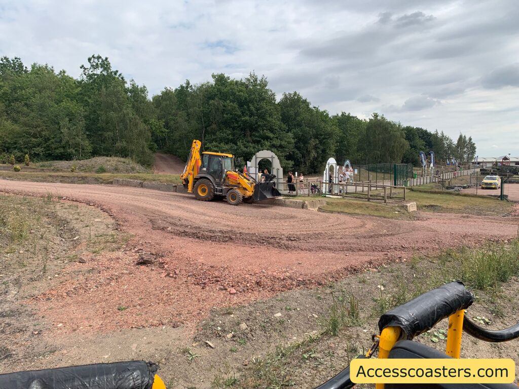 yellow backhoe loader on a dirt and gravel road.
