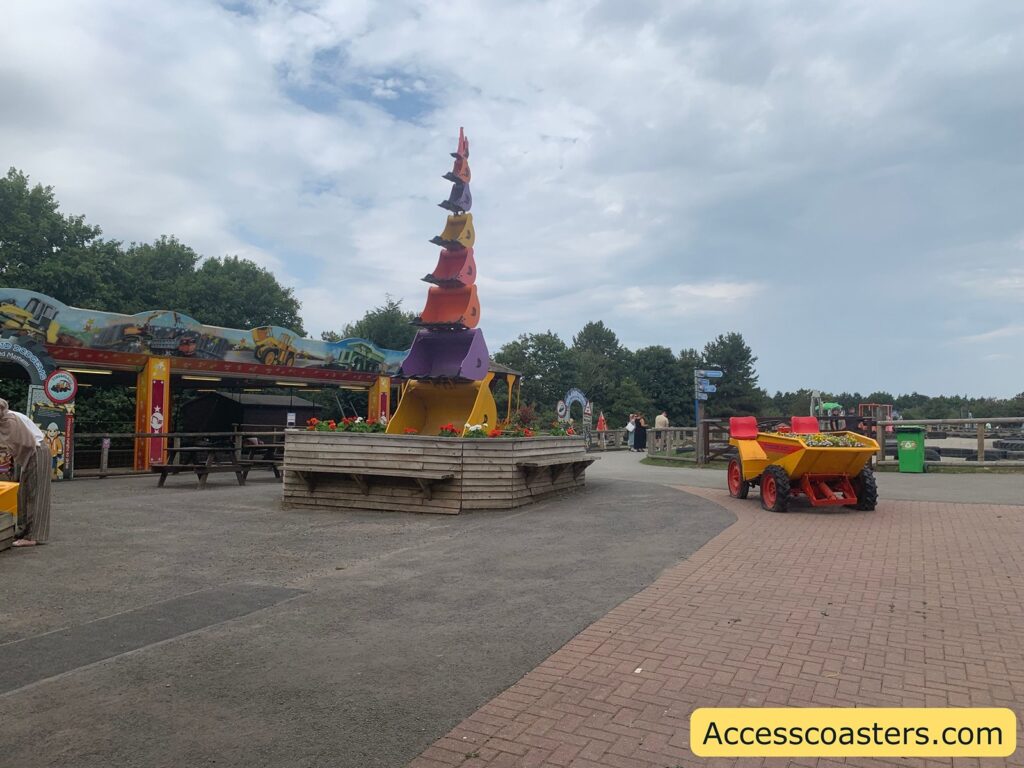 Glass entrance doors with a view outside to a paved courtyard. Just beyond the doors, a bright red and yellow children's ride-on digger or construction vehicle is parked.