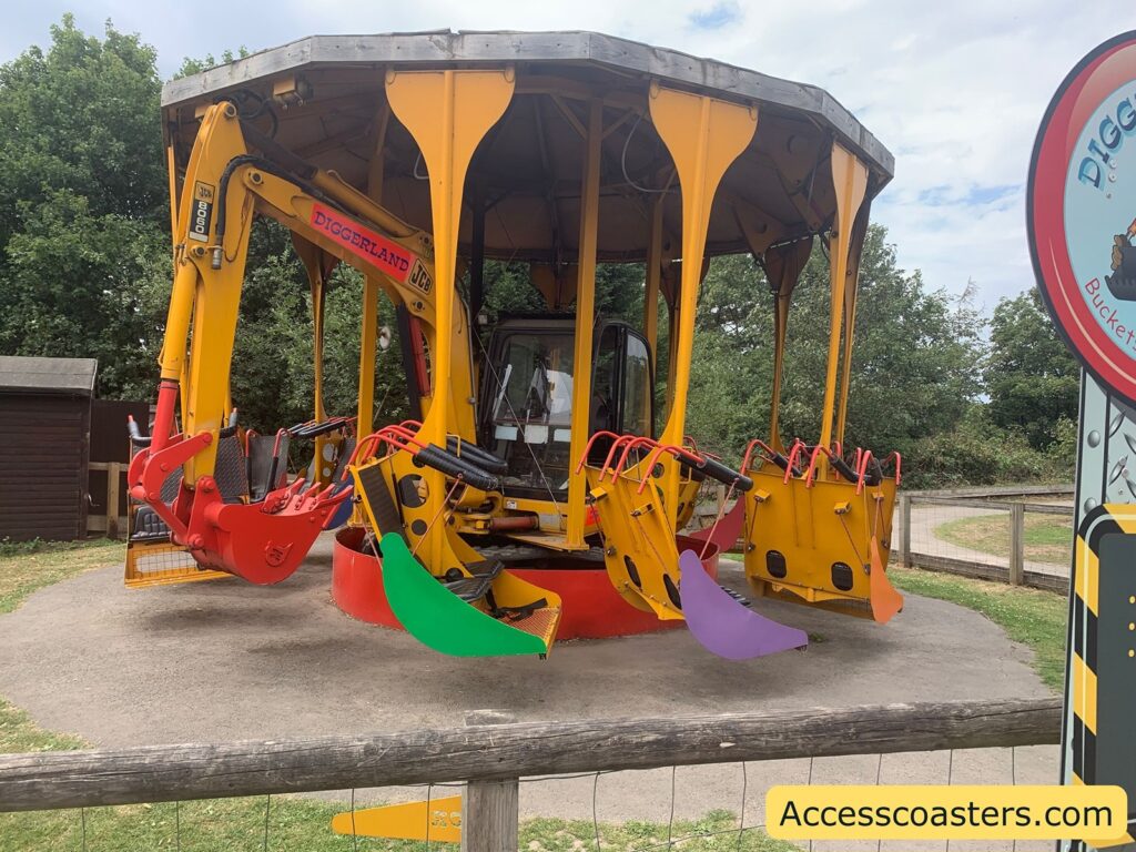 ride with a construction theme, styled to look like a small carousel made from the body and arms of a yellow JCB digger. The seats are attached to the end of the digger’s arms and buckets, painted in bright colors like red, green, purple, and orange.