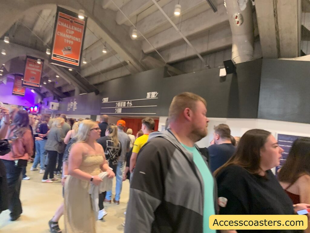 Indoor arena concourse crowded with people. A number of ice hocky banners are hanging from the ceiling