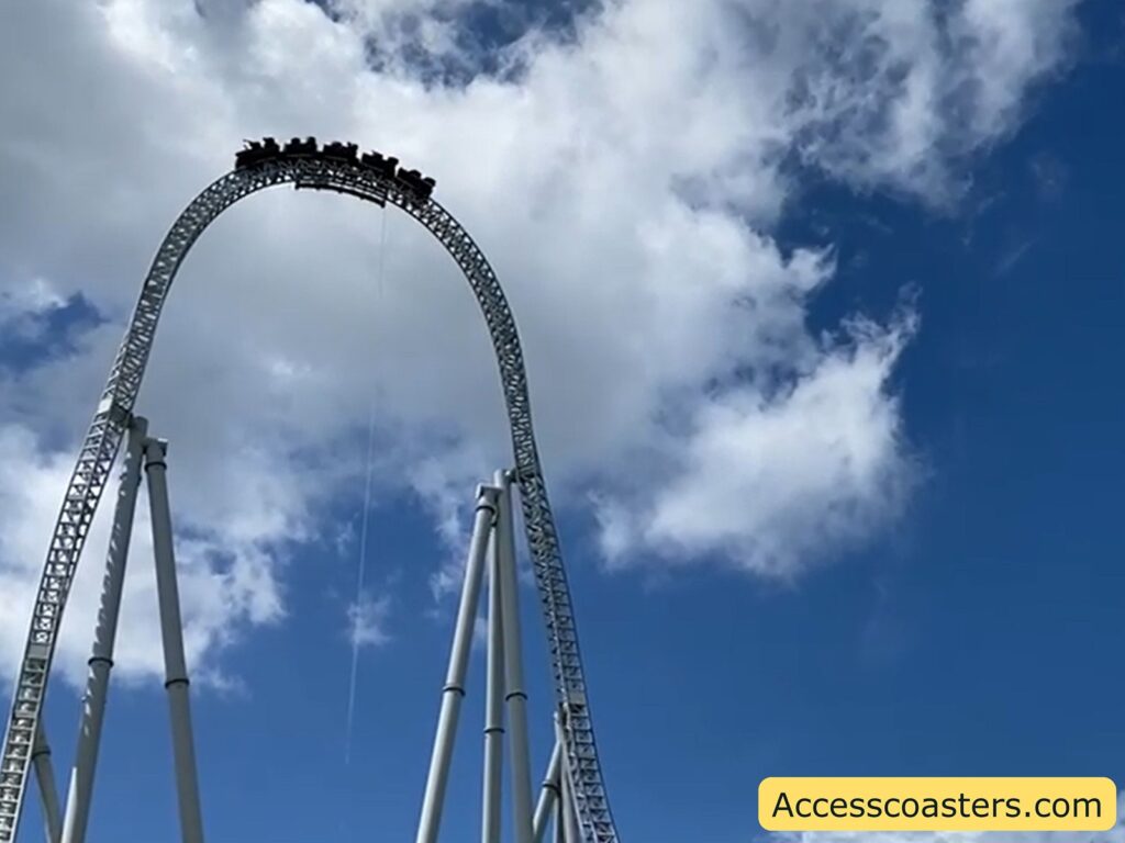 Stealth rollercoaster train launching up the towering vertical track against a bright blue sky.