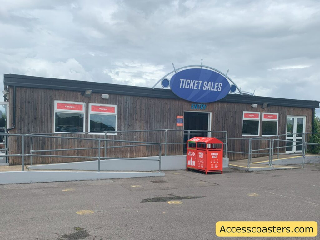 Wooden ticket sales building with a ramp for accessibility, several windows labeled "Tickets" and a large blue "Ticket Sales" sign above the entrance.