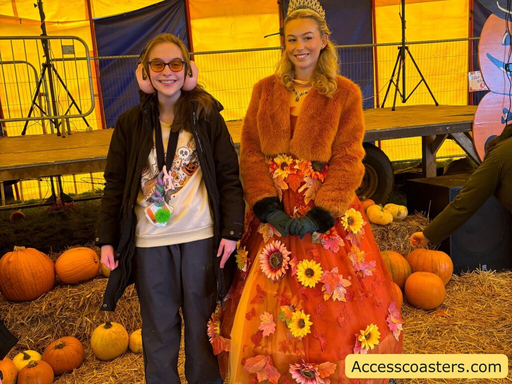 Image of Iona standing and smiling by a disply of pumpkin with the autum princess 
