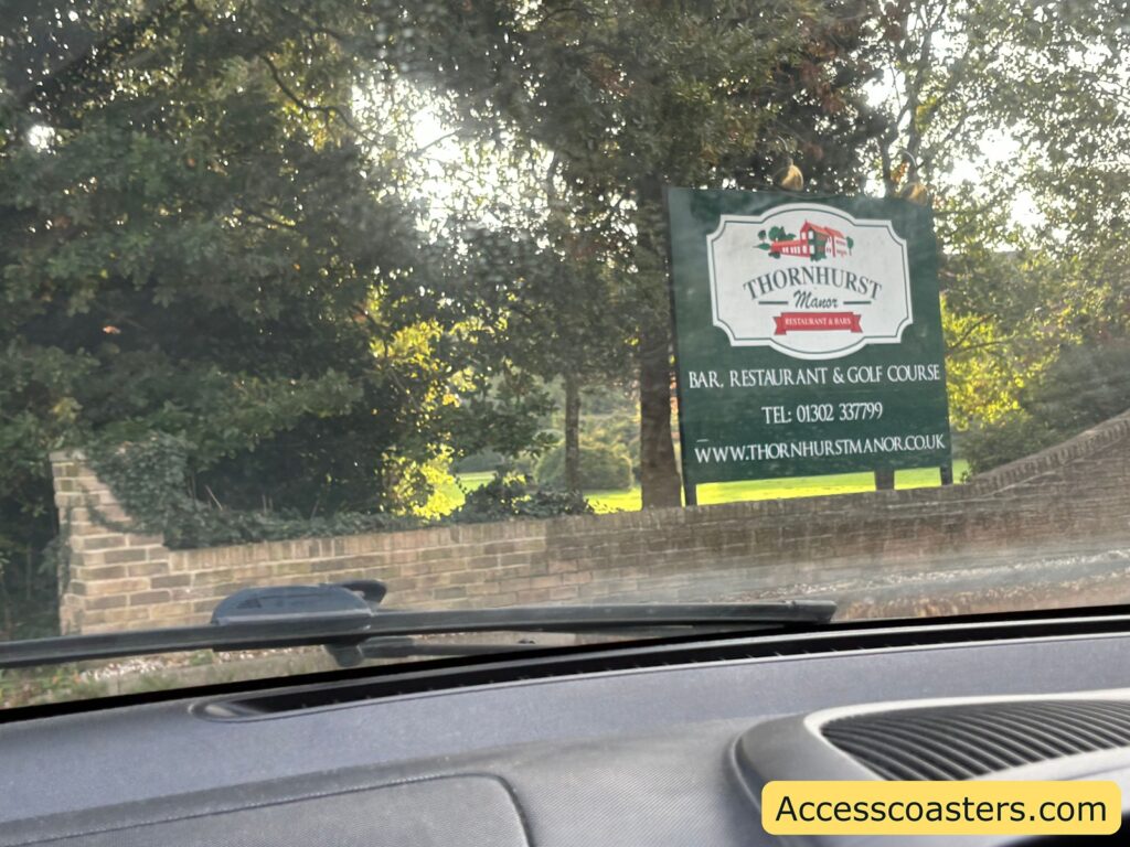 Green sign for “Thorndon Park Fear Factory” seen from a car dashboard at the entrance