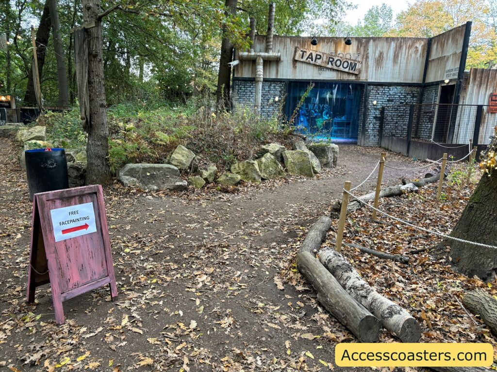 Outdoor pathway leading to the Tap Room bar building, surrounded by greenery with a small signboard on the path