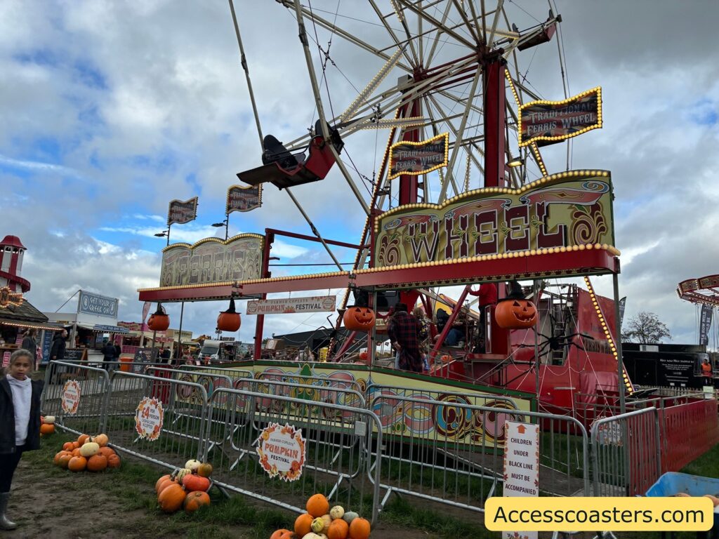 Vintage Ferris Wheel decorated with red and yellow, surrounded by pumpkins at the base