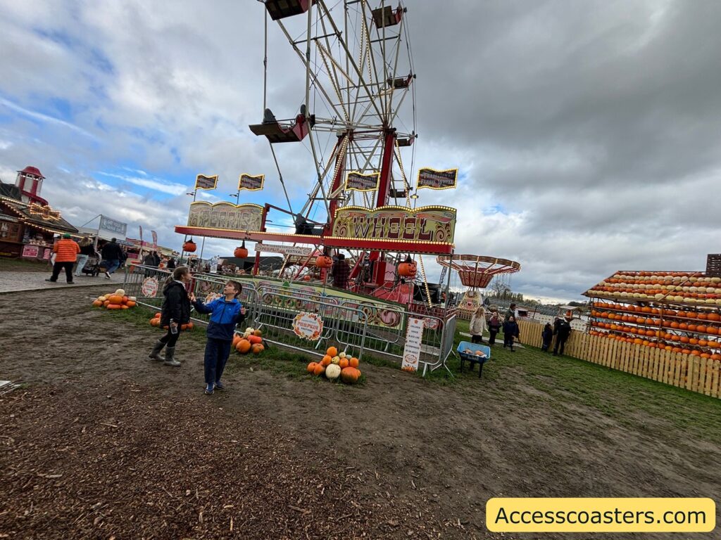 Wide view of the fairground showing the Ferris Wheel, fairground visitors, and pumpkin displays