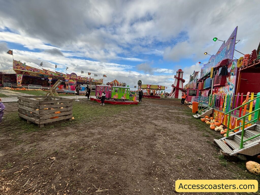 Fairground pathway featuring a collection of colorful rides and booths, with pumpkins displayed