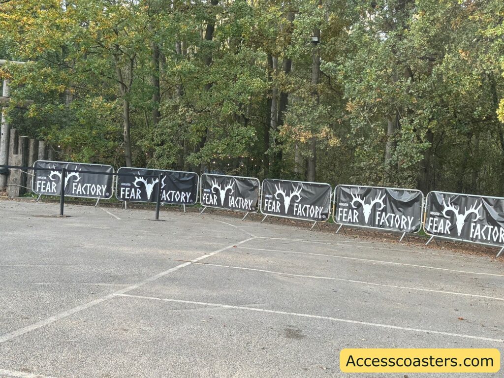 Parking area bordered by trees and black “FEAR FACTORY” branded barriers, designating the event parking zone.