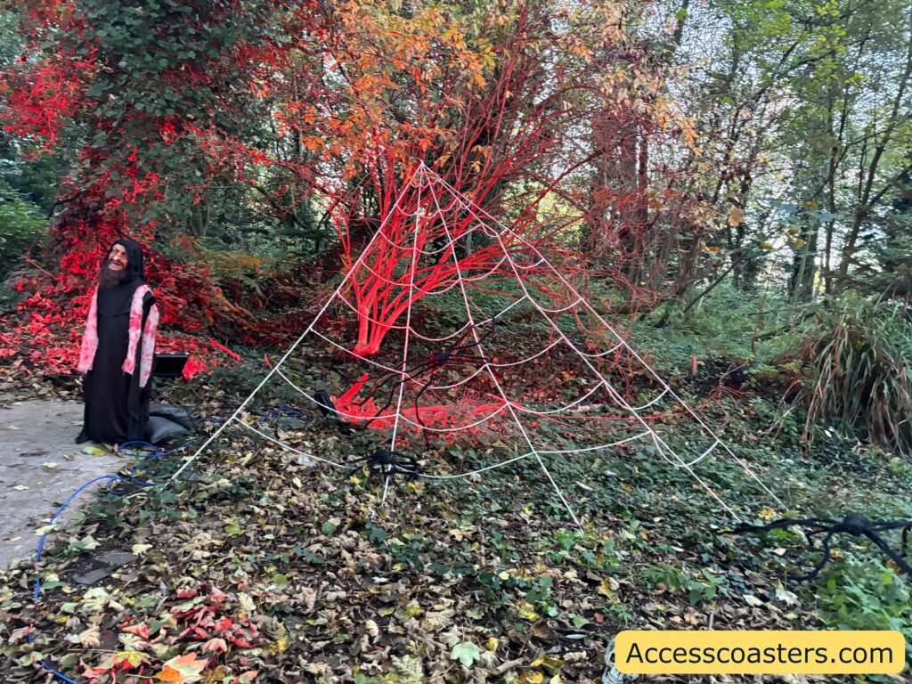 arge artificial spider web and red Halloween lighting among trees