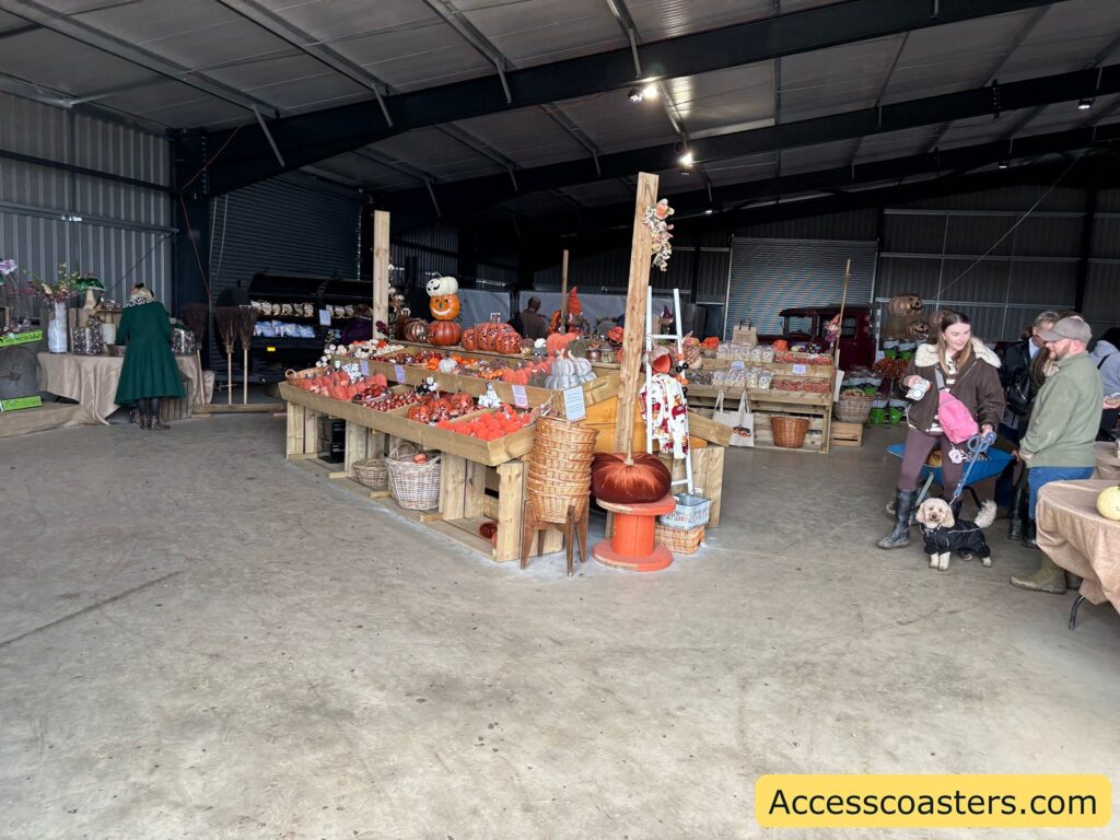 Inside the barn: tables and crates filled with pumpkins and festival goods, with people browsing.