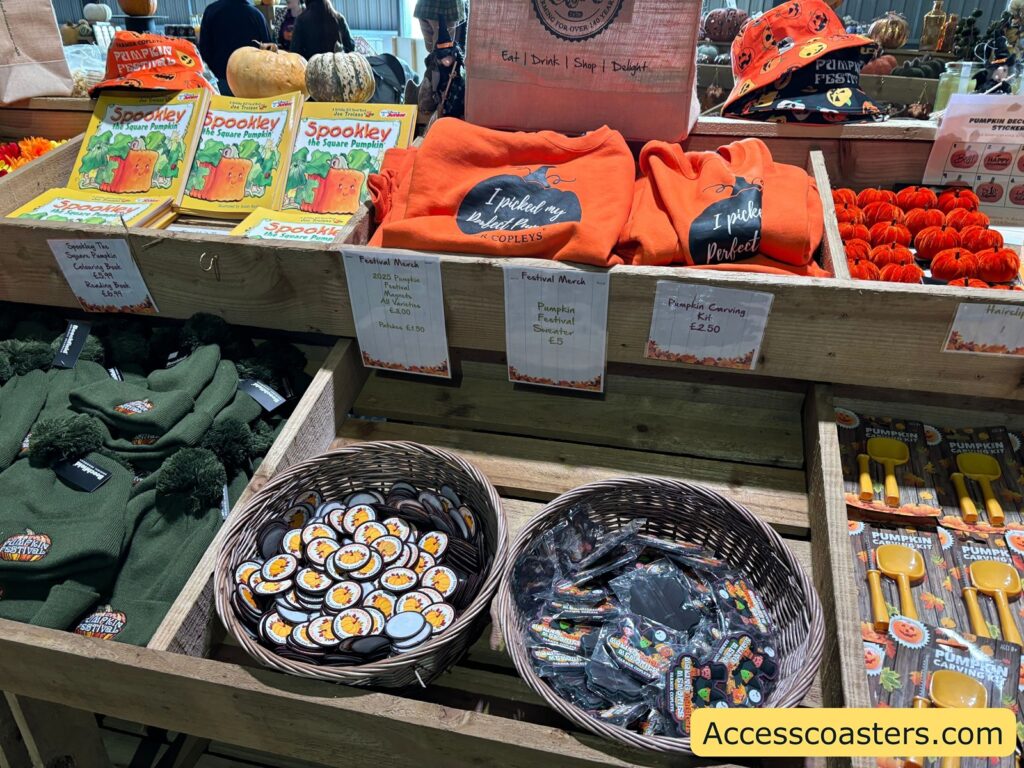 Crates with festival merchandise including badges, jumer and magnets  and pumpkins, labeled sections for different goods.
