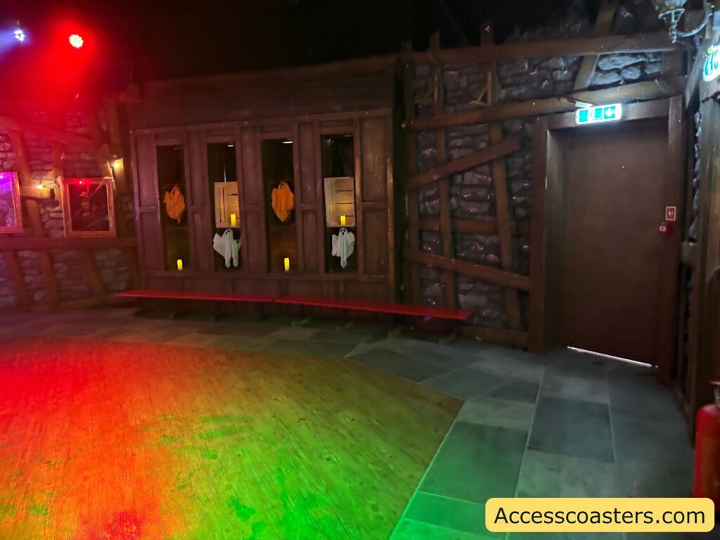 A Halloween-themed room with dark wooden walls, doors adorned with cutout hands, a glowing red and green floor,