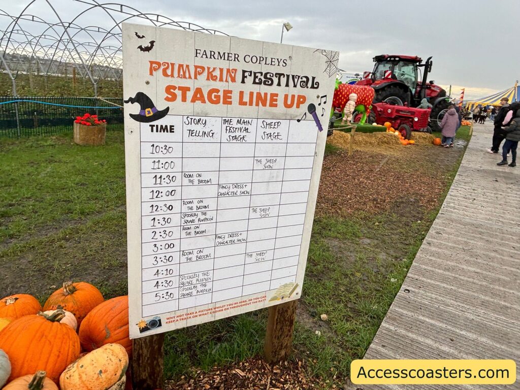 Signage listing the event stage times and pumpkin prices at the festival entrance