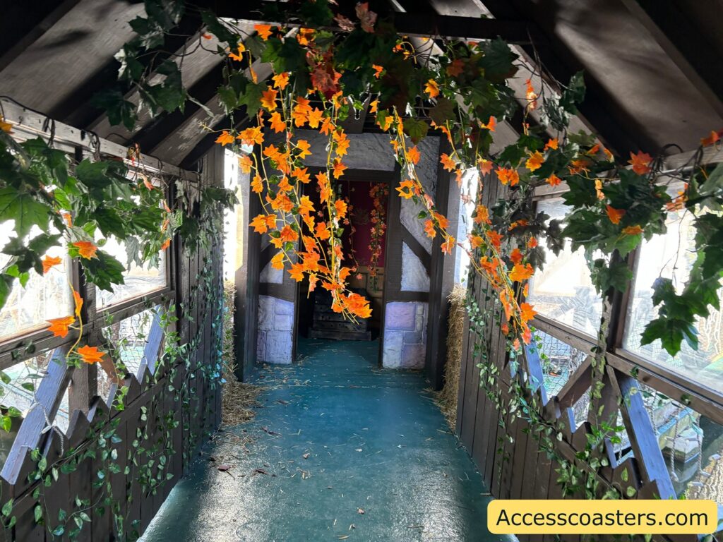 . A castle corridor decorated with green vines and hanging orange flowers, leading into the party room