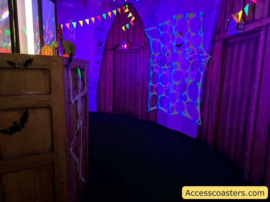 A hallway inside the castle, glowing with UV lights and decorated with neon-colored bunting and spiderweb designs.