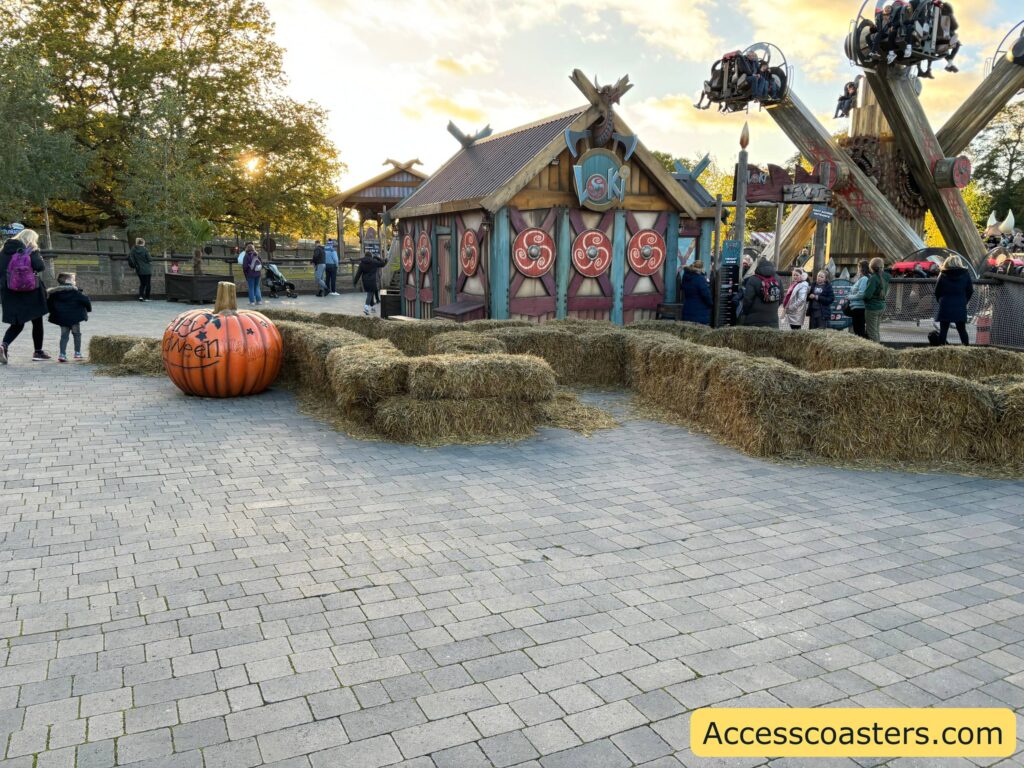 An outdoor plaza with a small maze made of hay bales and a large decorative pumpkin