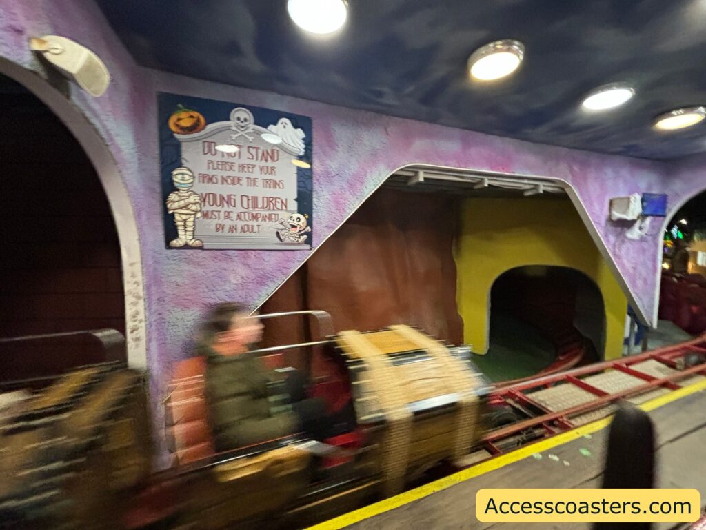 Themed tunnel section of the Spooky Express, with a rollercoaster cart entering a dark indoor area.