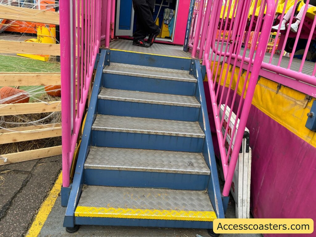 close-up of the stairs with a blue walkway and pink handrails leading up to the Sky Drop ride platform