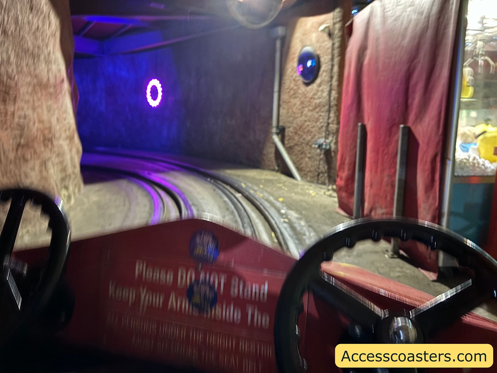 Tight interior view from inside a jet car, showing multiple small cars on the track in a dimly lit tunnel with bright lights overhead.