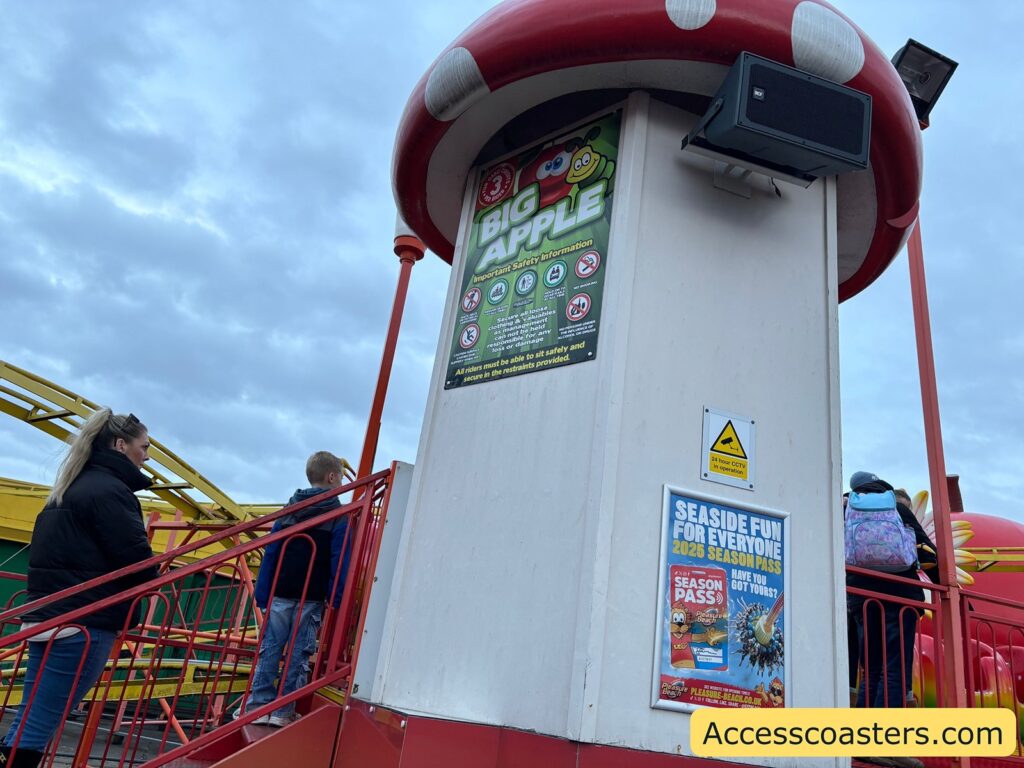 White and red-themed entrance tower with Big Apple Coaster ride restriction signage
