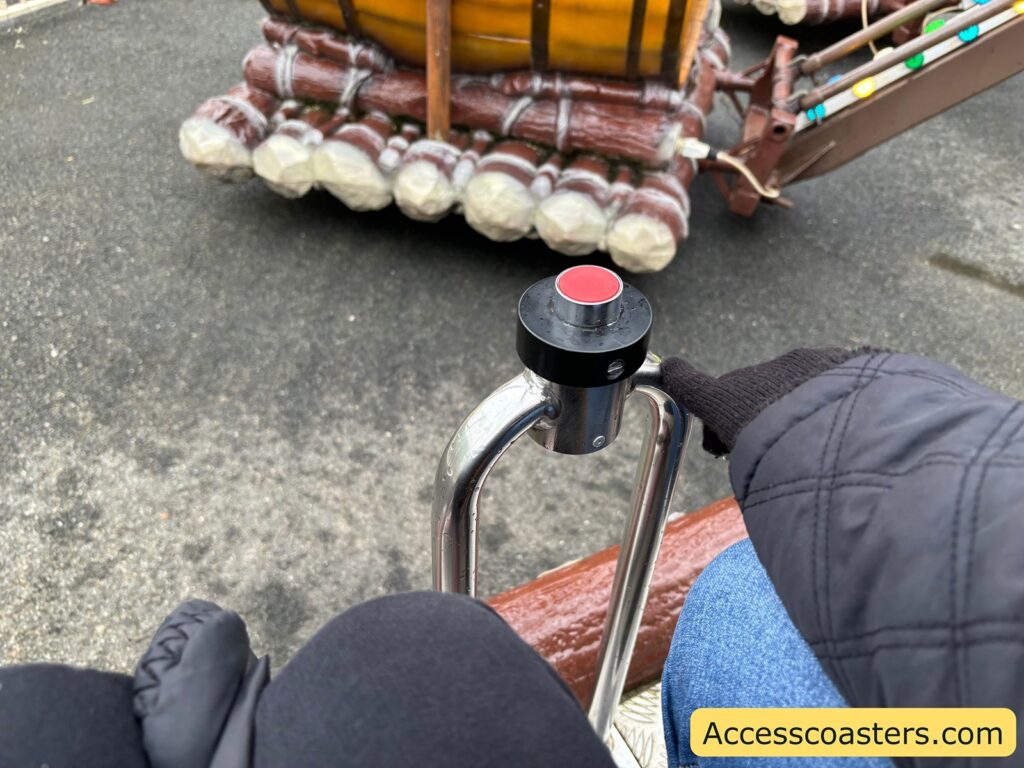close-up view from a rider's perspective on the Raft Ride, showing their legs, part of their lap, and a hand on the ride’s black control button.