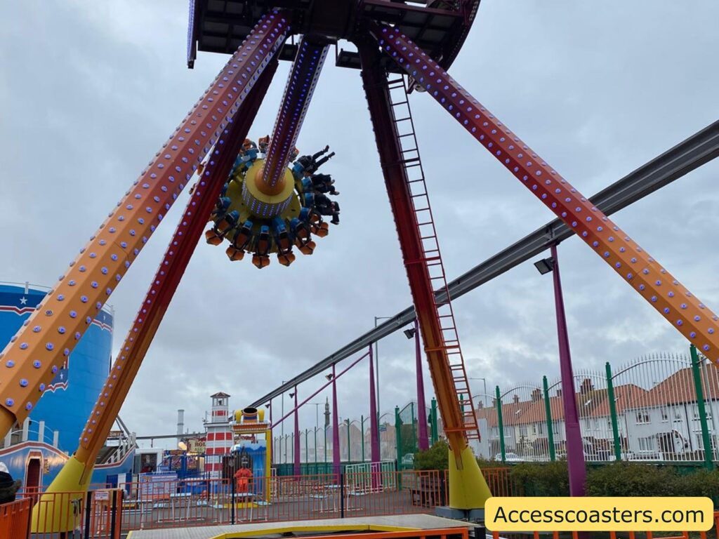 The Pendulum ride in mid-swing with riders held upside down at the highest point. The massive arm and structure are clearly visible