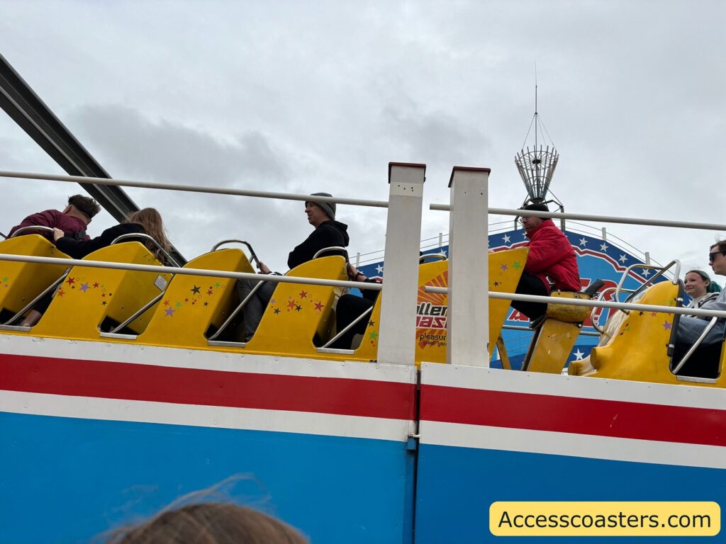 Side view of Roller Coaster train on the track with riders seated.