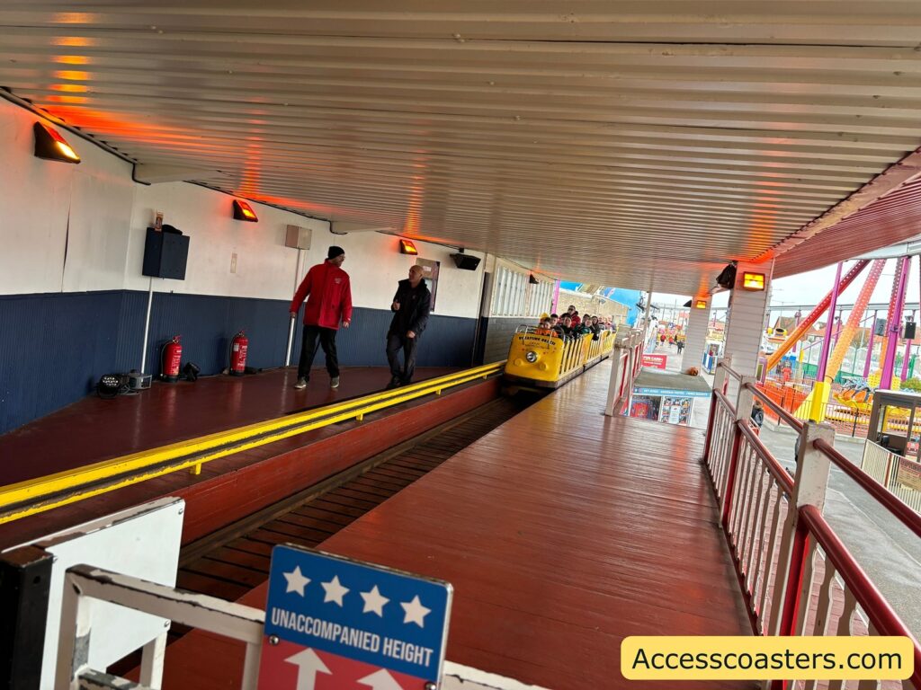 Wide yellow ramp inside the station, with people waiting to board the Roller Coaster.