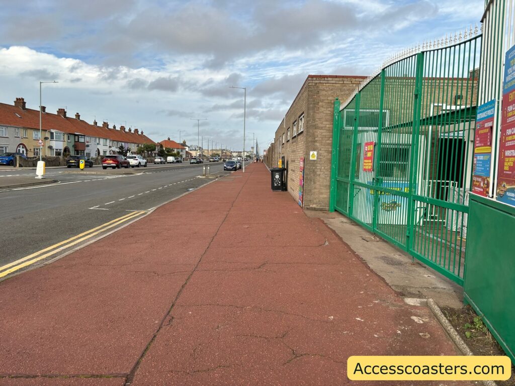 Wide pavement and road alongside the green fence at Great Yarmouth Pleasure Beach,